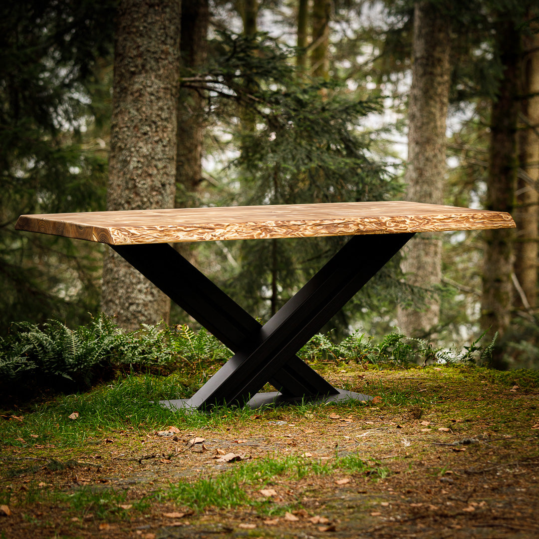 Geflammter Massivholz-Tisch mit Metallgestell, der im Wald steht