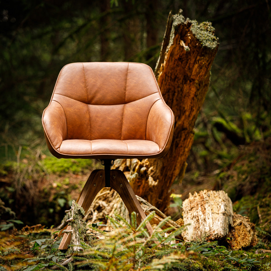 Brauner Lederstuhl mit Massivholz-Beinen, der im Wald steht