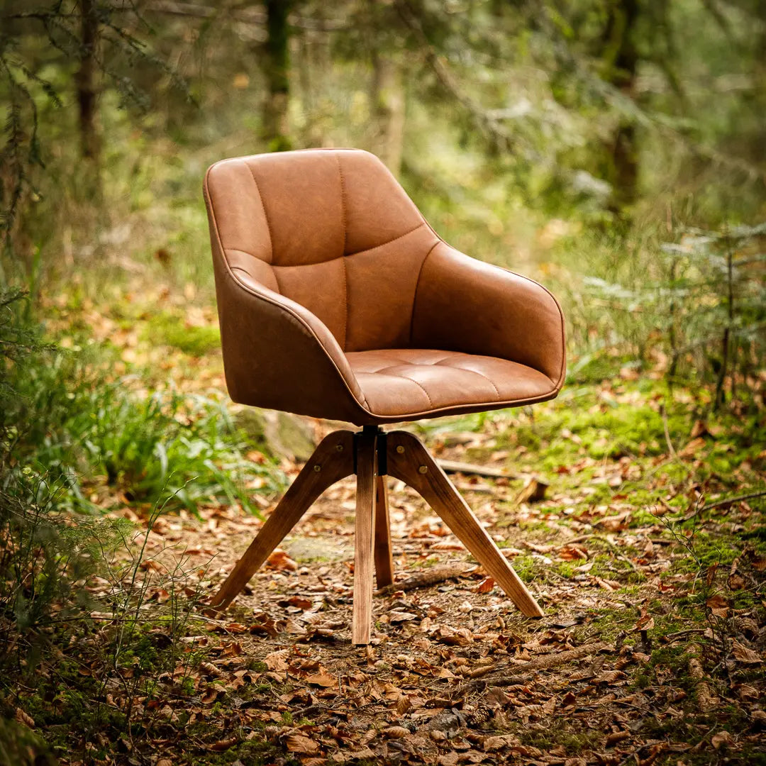 Brauner Lederstuhl mit Holzbeinen, der im Wald steht