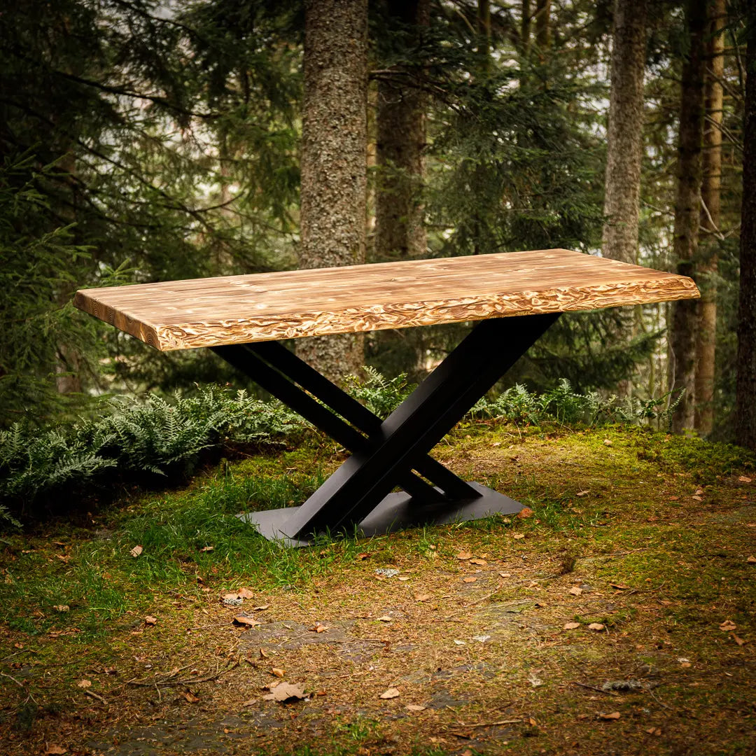 Geflammter Massivholz-Tisch mit Metallgestell, der im Wald steht